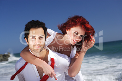 young couple at the beach giving piggy back