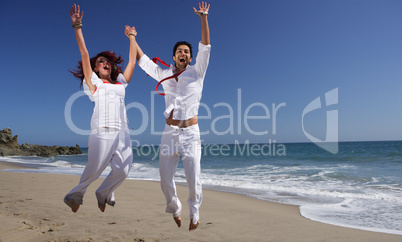 Young Couple at the beach jumping for joy