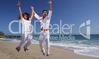 Young Couple at the beach jumping for joy