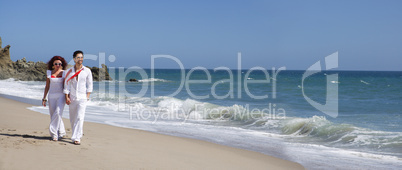 Young Couple at the beach walking while holding hands