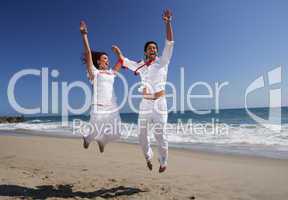 Young Couple at the beach jumping for joy