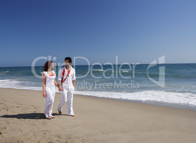 Young Couple at the beach walking while holding hands