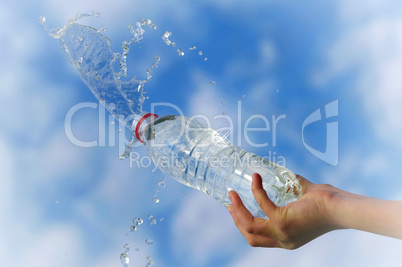 Spritzer und Tropfen aus der Mineralwasserflasche in der Hand