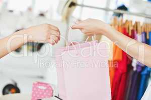 A saleswoman giving a shopping bag to a customer
