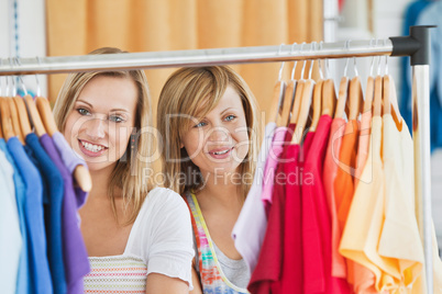 Beautiful female friends doing shopping choosing shirts