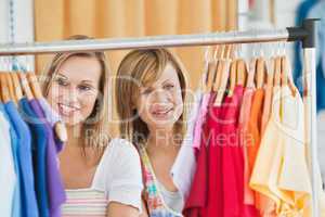 Beautiful female friends doing shopping choosing shirts