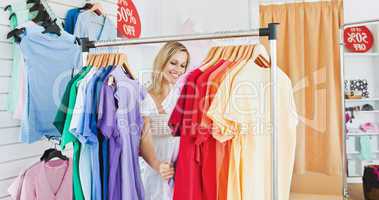Merry blond woman choosing colorful clothes