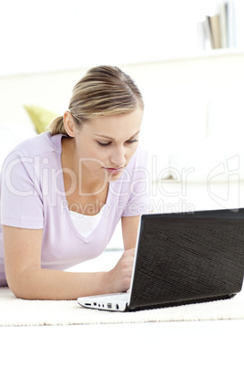 Concentrated woman using her computer lying on the floor