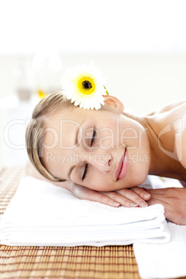 Blond young woman with flowers in her hair with closed eyes in a