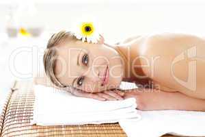 Glowing young woman with flowers in her hair on a massage table
