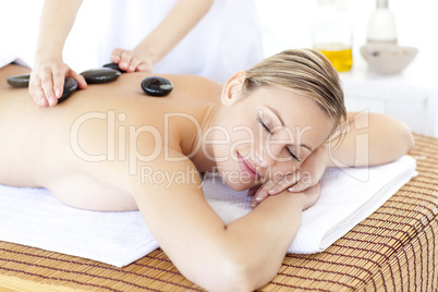 Pretty young woman receiving a massage with hot stone