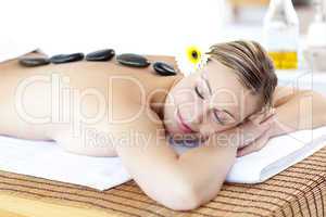 Happy young woman with hot stone on her back and closed eyes
