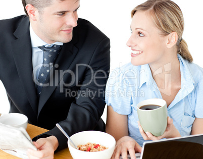 Affectionate young couple having breakfast using their laptop