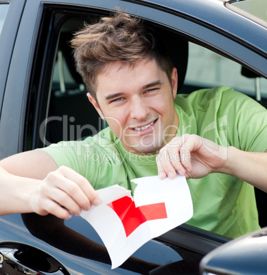 Happy young male driver tearing up her L sign