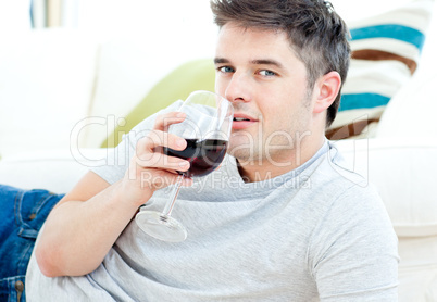 Handsome man lying on the floor drinking wine