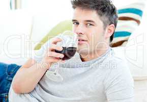 Handsome man lying on the floor drinking wine
