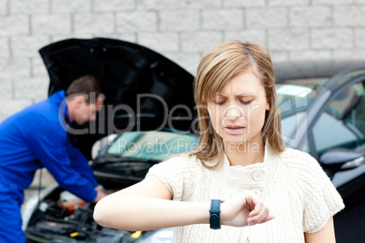 Man repairing car of pretty woman