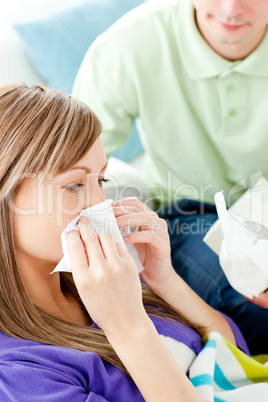 Sick woman with tissue lying on a sofa