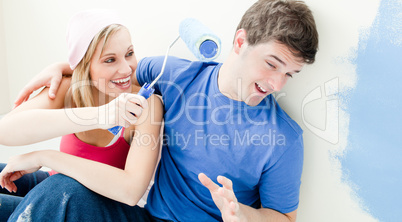 Laughing couple having fun while painting a room