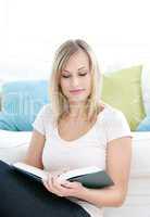 Concentrated young woman reading a book on the floor