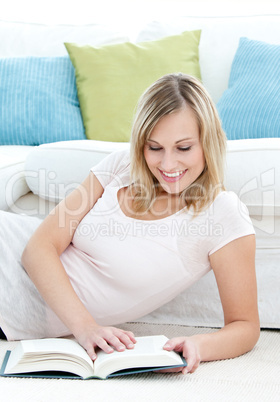 Bright blond woman reading a book on the floor