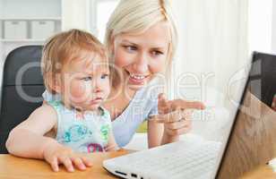 Blond mother having fun with her daughter in front of the laptop