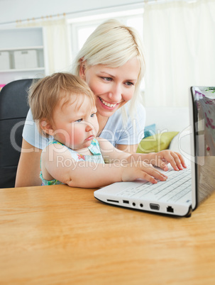 Blond mother and her daughter sitting in front of the laptop