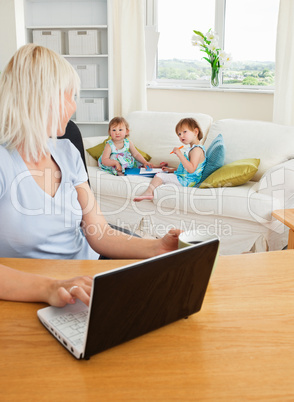 Blond mother working at laptop