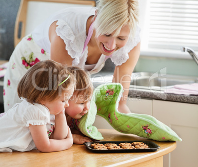 Smiling woman baking cookies with her daughters