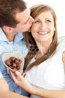 Handsome man kissing his girlfriend holding chocolote