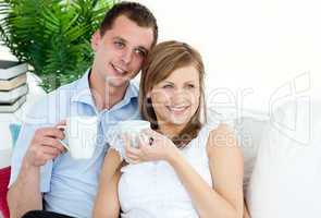 Attentive young couple drinking coffe sitting on a sofa