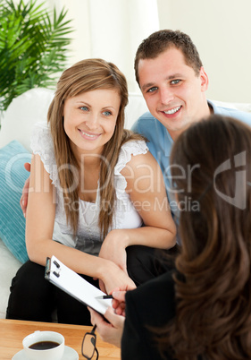 Bright couple concluding a car contract with a female dealer