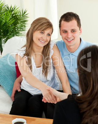 Happy couple concluding a contract with a female dealer