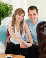 Happy couple concluding a contract with a female dealer