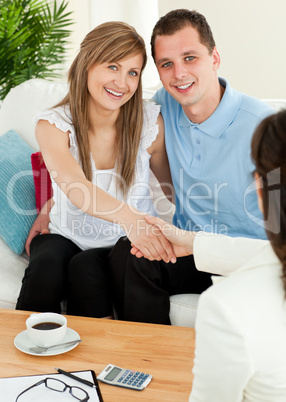Attractive couple concluding a car contract with a female dealer