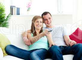 Charismatic man embracing his girlfriend while watching tv