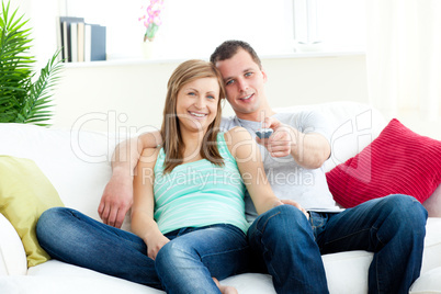 Affectionate man embracing his girlfriend while watching tv