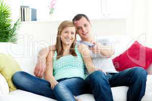 Affectionate man embracing his girlfriend while watching tv