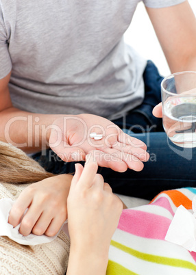 Close-up of young man giving pills to his morbid girlfriend