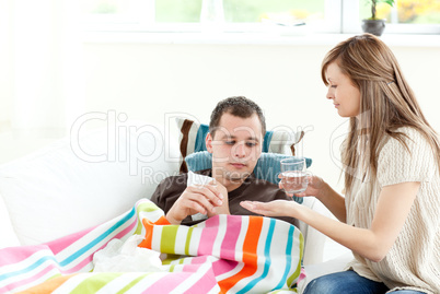 Caring girlfriend giving his sick boyfriend pill