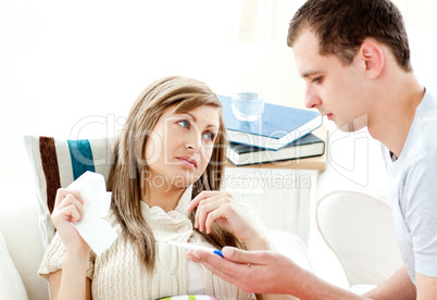 Loving boyfriend holding a thermometer of his ill girlfriend