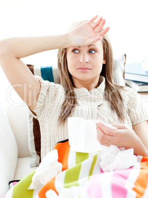 Sick young woman having fever lying on the sofa