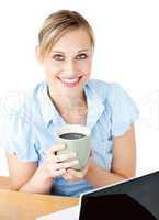 Glowing businesswoman drinking coffee smilng at the camera