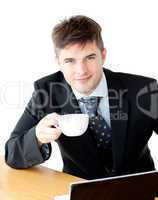 Charming young businessman holding a cup smiling at the camera