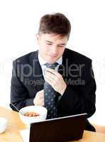 Attractive young businessman making his tie looking at his lapto