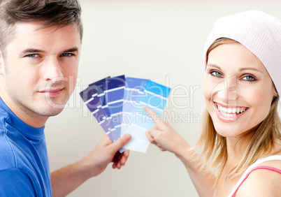 Cheerful couple with color samples for painting a room