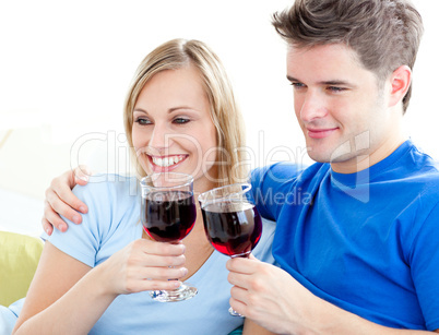 Affectionate couple drinking wine sitting on a sofa