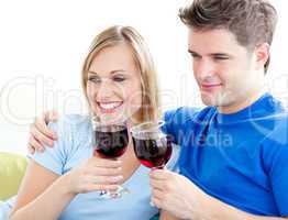 Affectionate couple drinking wine sitting on a sofa