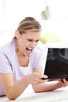 Furious young woman screaming at her laptop