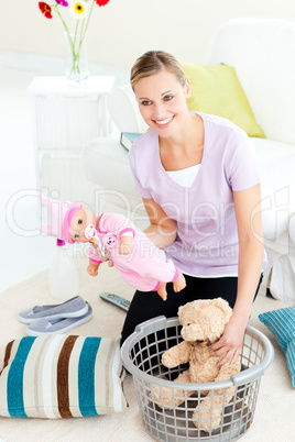 Cheerful caucasian woman putting toys into a basket